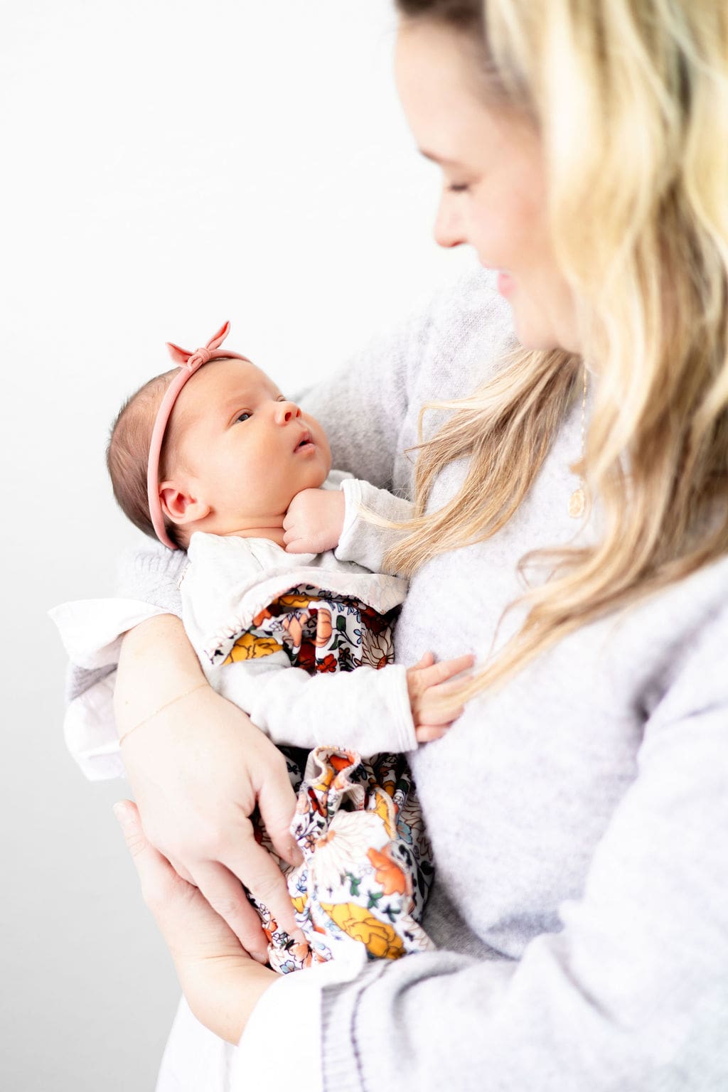 A newborn baby looks up at mom while laying in her arms in a colorful swaddle after working with lactation consultants in austin