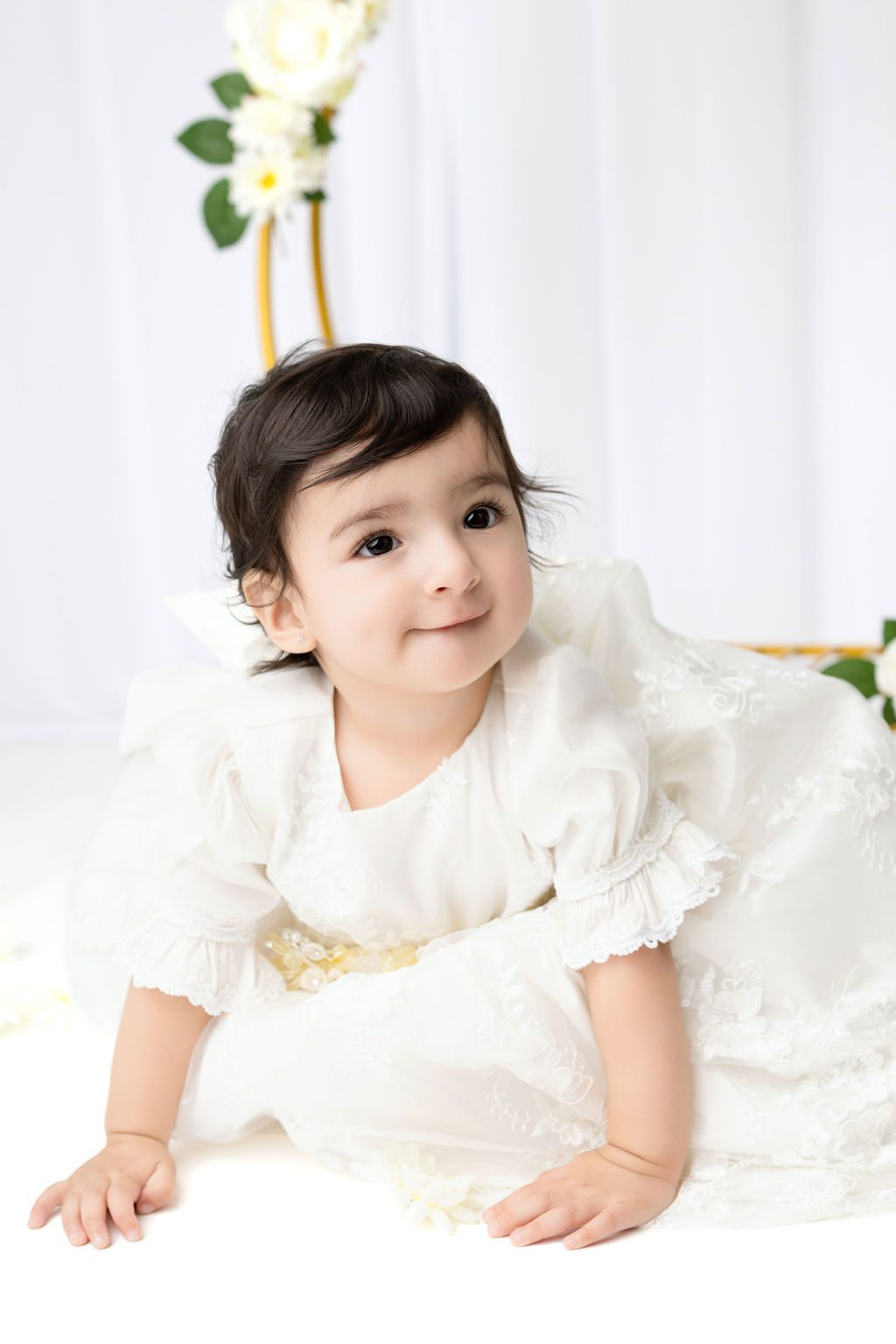 A toddler girl in a white dress crawls on the floor after exploring daycares in austin